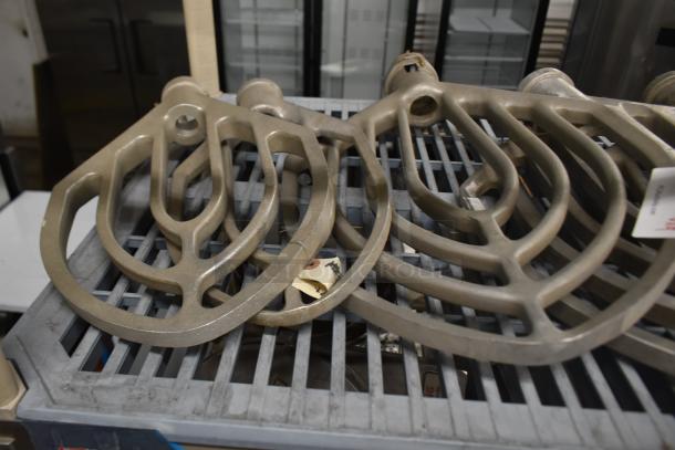 Nine Hobart mixer paddle attachments, metal, used condition, visible wear. Suitable for commercial mixing tasks.