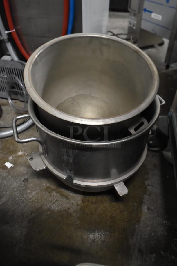 Stacked metal mixing bowls for Hobart mixer, showing wear, with handles.