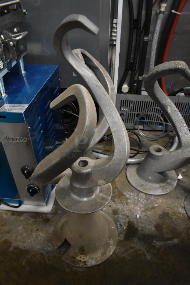 Five Hobart mixer dough hook attachments in used condition, gray metal, suitable for commercial mixers.