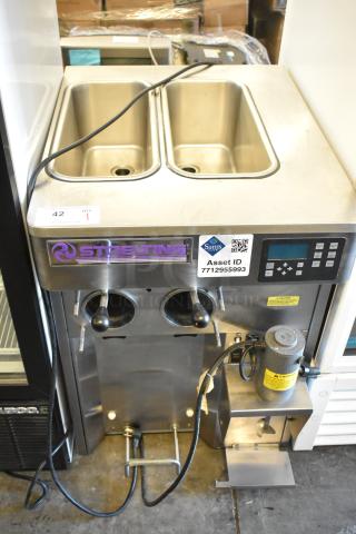 Stoelting stainless steel commercial countertop soft serve ice cream machine with drink mixing attachment, digital controls, visible asset ID tag.