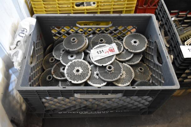 110 various meat grinder plates in a storage crate, shown in used condition with visible perforations and ID tag.