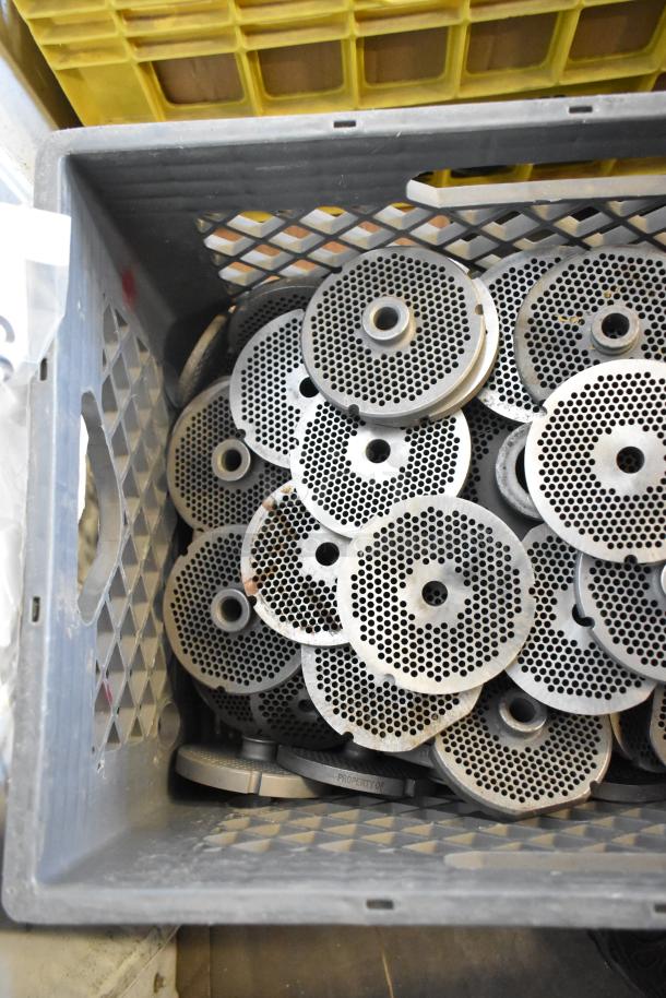 Metal plates for meat grinders, in good condition, stored in a gray crate. Includes 110 various plates.