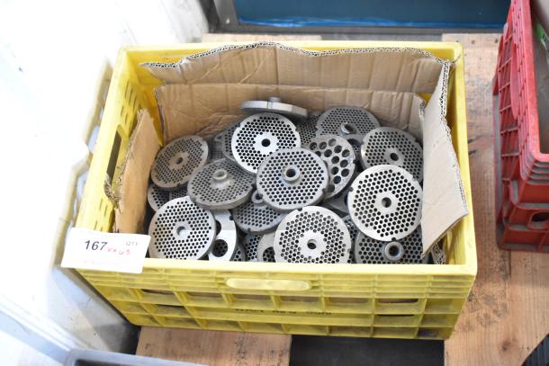 Box of 63 various meat grinder plates, metal, used condition, in a yellow crate with auction tag indicating quantity.
