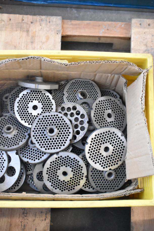 Box of 63 metal meat grinder plates with various hole patterns, in used condition.
