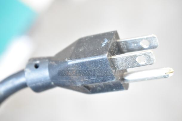 Close-up of a black three-prong electrical plug, showing slight wear.