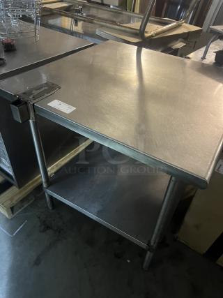 Stainless steel table with can opener bracket, measures 36x36x35-½ inches, used condition, visible label on surface.