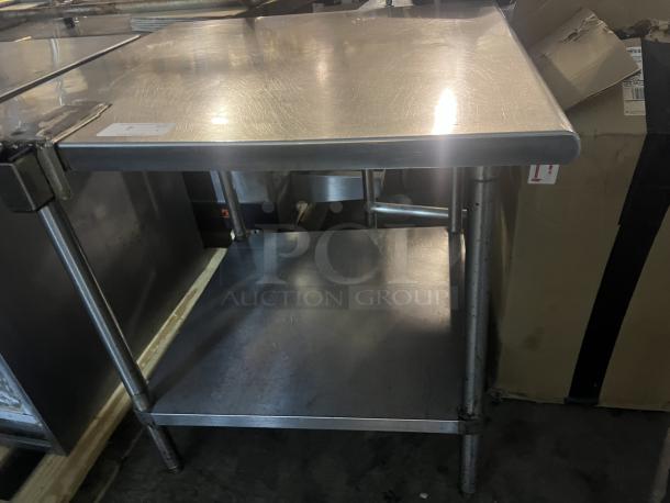 Stainless steel table with can opener bracket. Measures 36x36x35½ inches. Minor surface wear, sturdy construction.