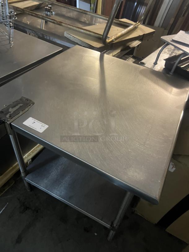 Stainless steel table with can opener bracket, 36x36x35½ inches, sturdy condition, features a lower shelf for storage.
