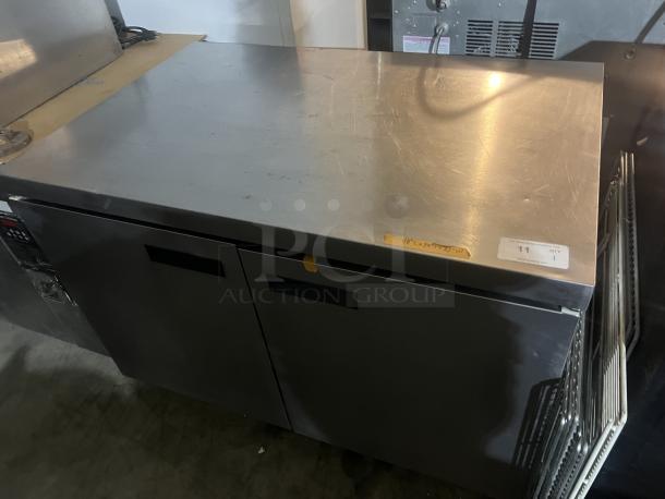 Stainless steel two-door refrigerator prep table with worktop, 48 x 34 x 32 inches. Good condition, minor surface scratches.
