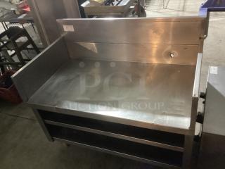 Stainless steel base with backsplash, 48x27x42 inches, features durable construction with shelves, light wear shown.
