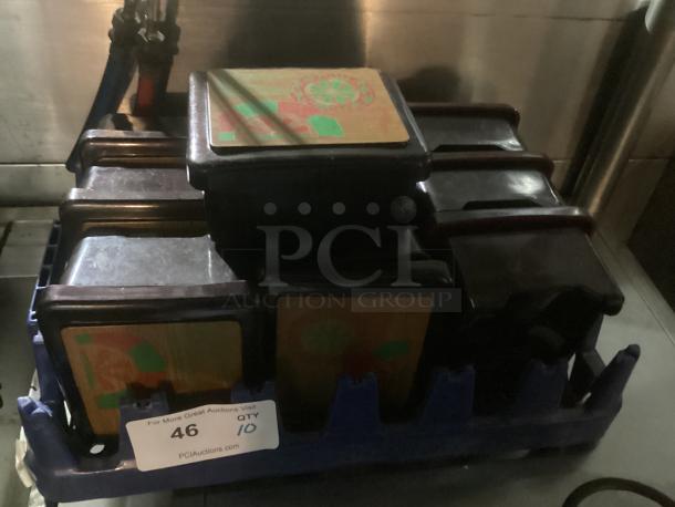 Set of 10 plastic trinket boxes with decorative lids, housed in a blue crate. Each box features colorful designs. Auction quantity: 10.