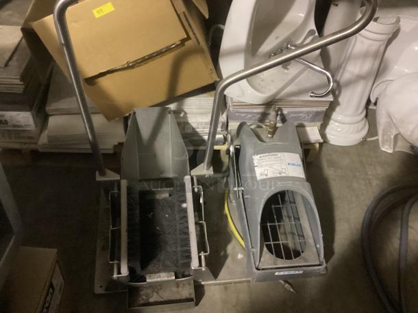 Eco Lab foot scrubbers in used condition, featuring metal handles and brushes, with visible Eco Lab branding.