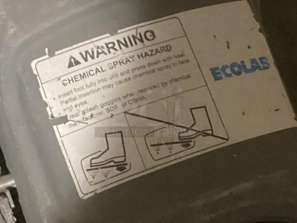 Eco Lab foot scrubber with warning label indicating chemical spray hazard. Worn condition, visible manufacturer logo.
