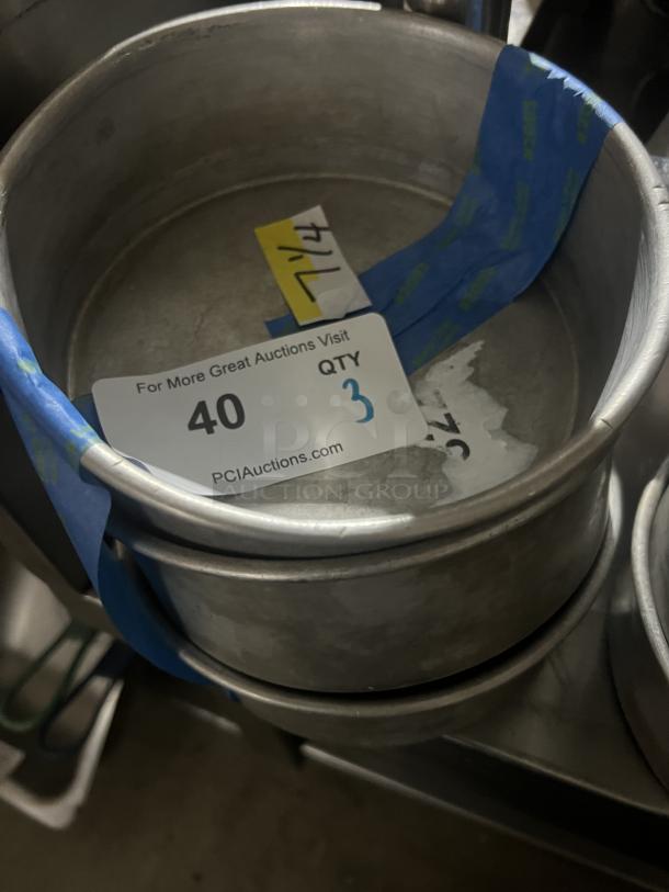 Three stacked 7-1/4" cake pans with auction tag indicating quantity 3. Appears used, visible tape and markings.