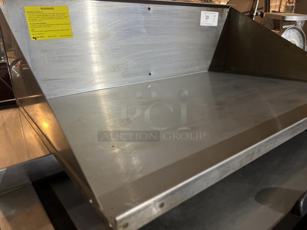 Stainless steel wall mount shelf, 34x21.5x10 inches, minimal wear. Visible yellow warning label, good condition.