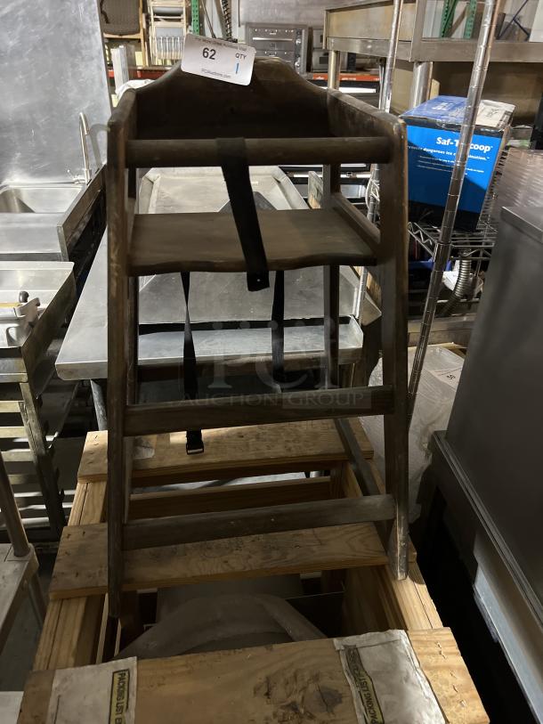 Wooden high chair with safety strap, vintage look, visible wear, sturdy construction. Auction tag indicates item number 62.