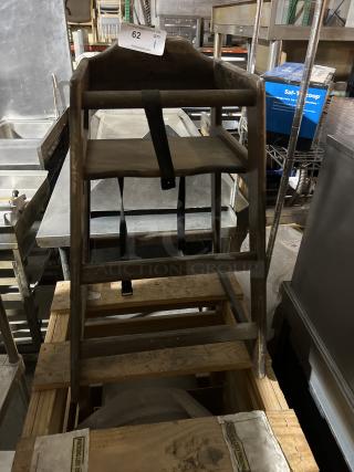 Wooden high chair with safety strap, vintage look, visible wear, sturdy construction. Auction tag indicates item number 62.