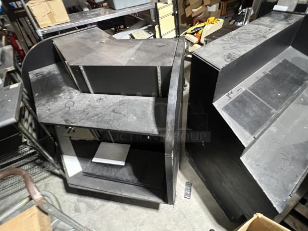 Black 2-piece merchandise display with shelves, showing signs of wear, suitable for retail use or storage.