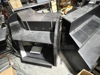 Black 2-piece merchandise display with shelves, showing signs of wear, suitable for retail use or storage.