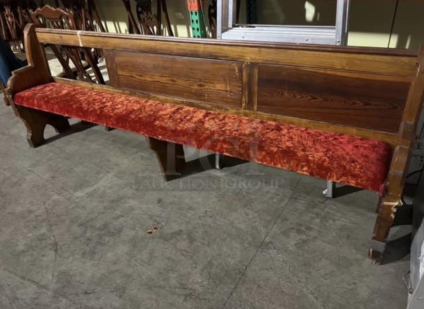 Antique church pew with crushed red velvet seat, wooden frame, and ornate carvings. Good condition, historically significant.