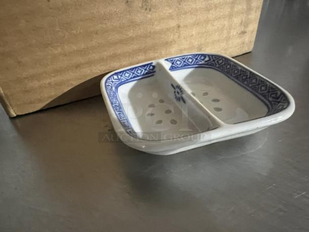 White ceramic sauce dish with blue geometric border, 2 compartments, slight interior spots, good condition.
