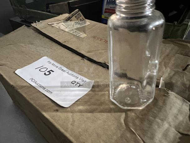 Clear glass salt and pepper shaker on a cardboard box, no cap, condition appears used. Auction label indicates lot 1/5.