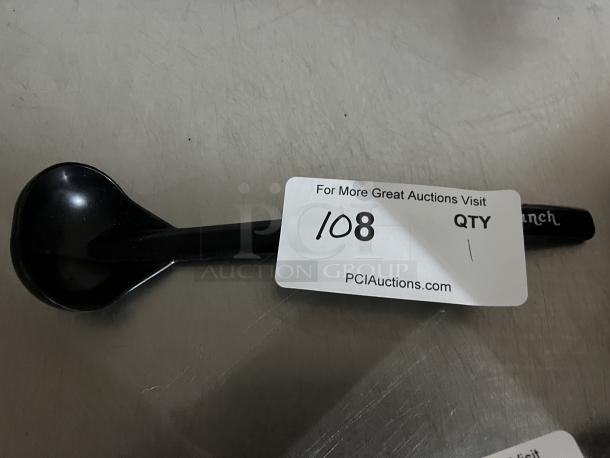 Black plastic ranch ladle, used condition, with slight wear. Tag reads "For More Great Auctions Visit PCIauctions.com."