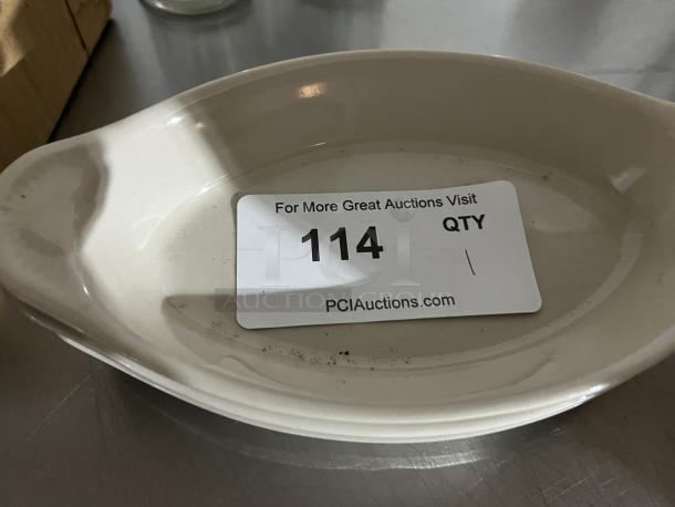White oval ceramic au gratin dish with minor scuff marks. Auction tag reads "114, pciauctions.com."