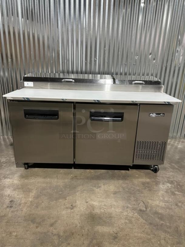 Brand new Blue Air BAPP67 67" stainless steel refrigerated pizza prep table, with cutting board, food pans, and casters.