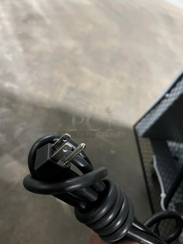 Close-up of coiled power cord for Blue Air BKGM12HC refrigerator, showing a three-prong plug, on a gray background.