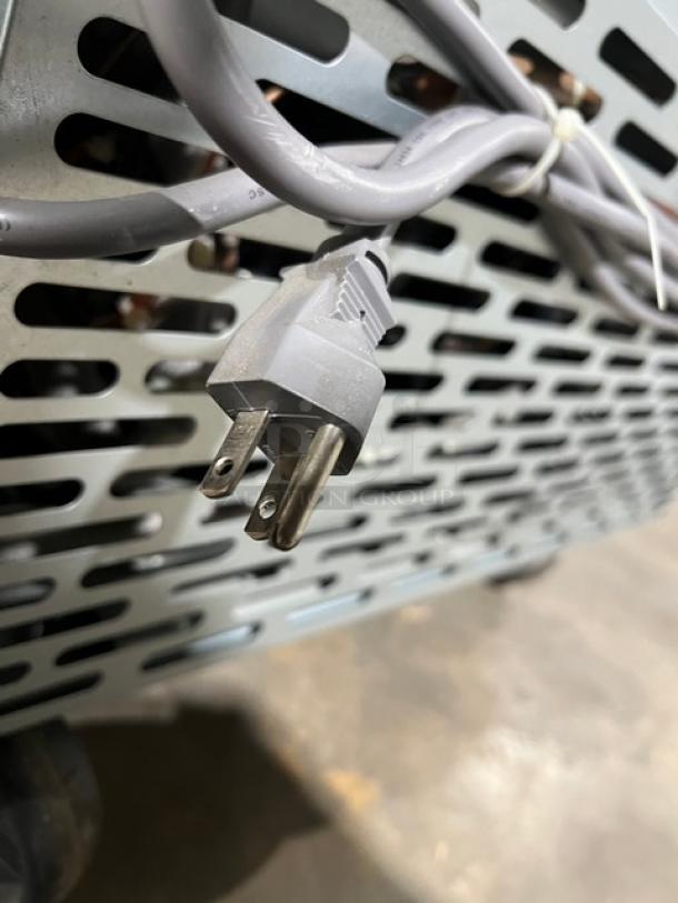 Brand new Blue Air BAUR28 undercounter refrigerator, stainless steel, on casters, with poly coated rack, 115V plug visible.