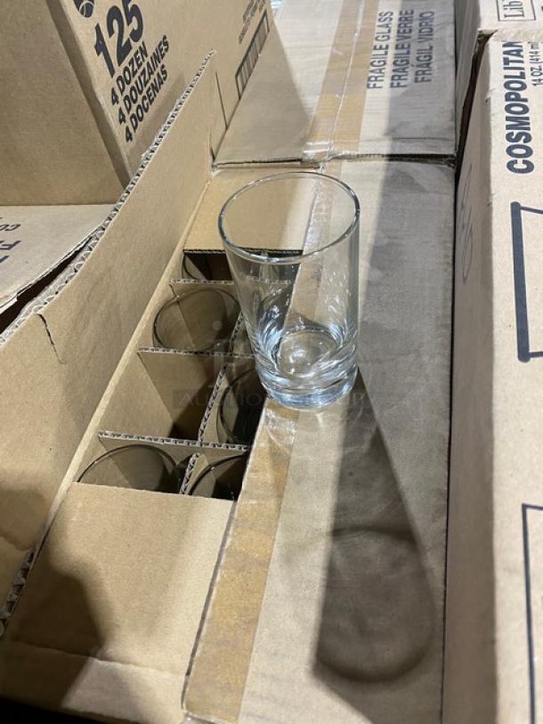 Mixed pallet of new Libbey glassware, includes 12 oz stemmed pilsner, teardrop flutes, beverage, and highball glasses in cases.