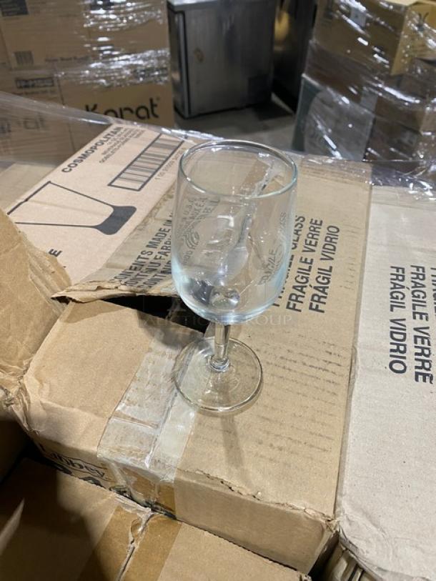 Libbey clear stemmed glass atop packed brown boxes labeled "FRAGILE VIDRIO." Boxes show other glass models included in auction.