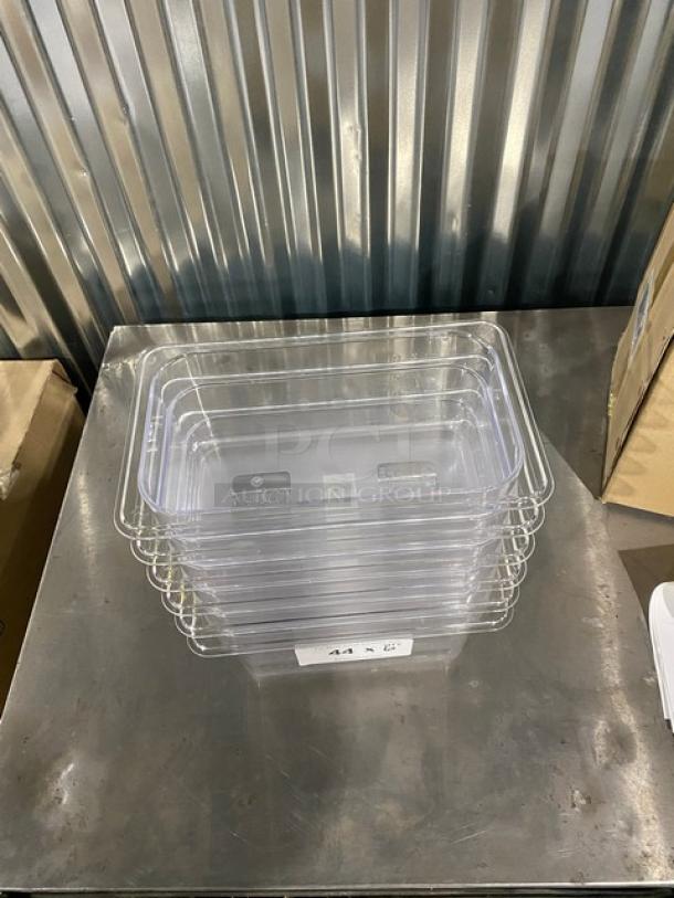 Brand new Winco SP7404 clear polycarbonate 1/4-size food pans, 4" deep, stacked on a metal surface.