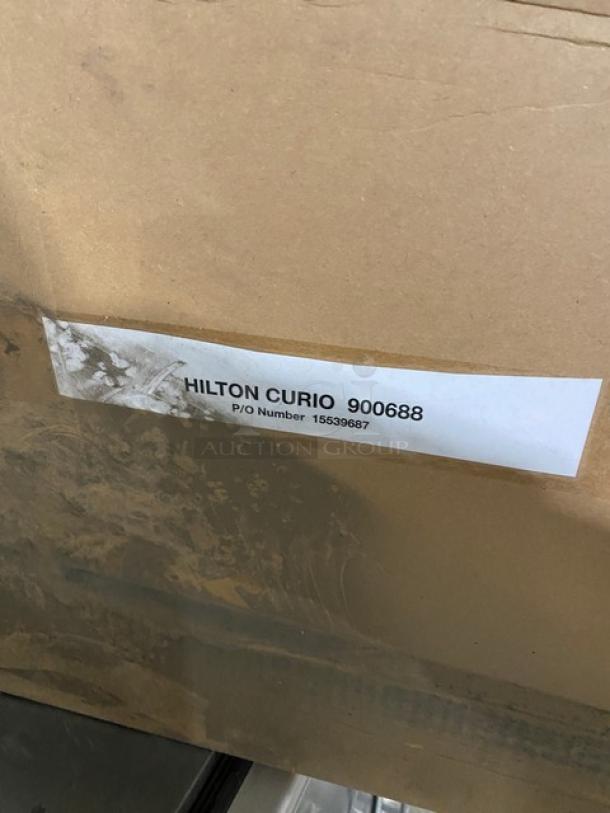 Brand new Marcus Rack commercial stainless steel wine shelves in original packaging. Label reads "Hilton Curio 900688."