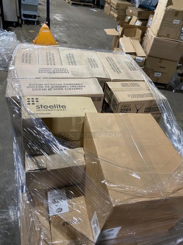 Mixed pallet of brand new commercial glassware including Libbey Super Bowl glass, wine goblets, mini martini glasses, and oil & vinegar set, wrapped and labeled in warehouse setting.