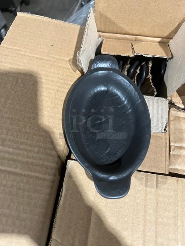 Box of brand new black oval serving dishes inside an open cardboard box. Quantity and other items not visible.
