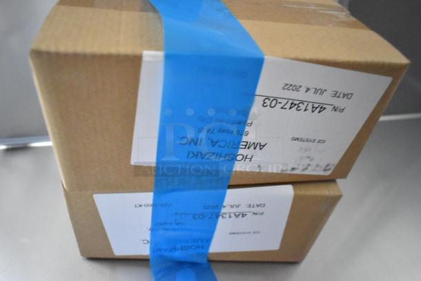 Cardboard boxes with blue tape and labels indicating "Hoshizaki America Inc." with date and part number details.