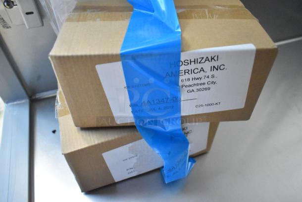 Close-up of Hoshizaki cooler packaging with labels showing address and part number, sealed with blue tape.