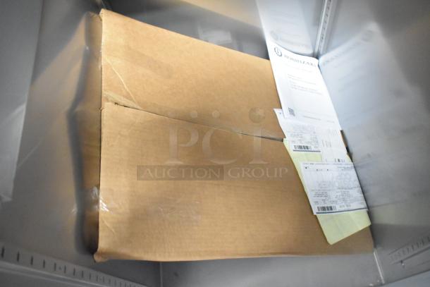 Brand new Hoshizaki R1A-FS commercial cooler in packaging. Includes tags and labels indicating model and specs. 115V, 1 Phase.