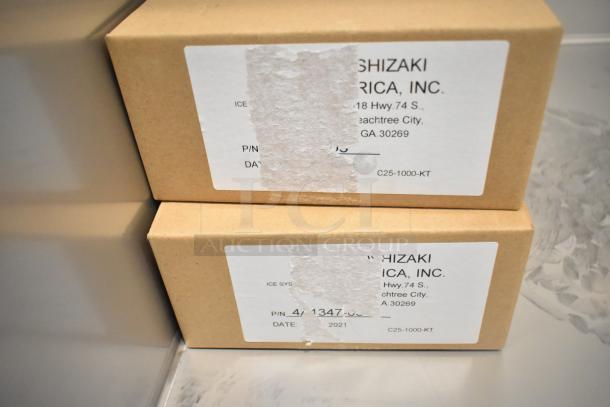 Cardboard boxes with Hoshizaki America labels, indicating part number and address, inside cooler.