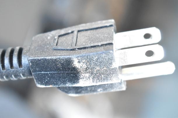 Close-up of a dusty black electrical plug, suitable for 115 volts, 1 phase appliances.