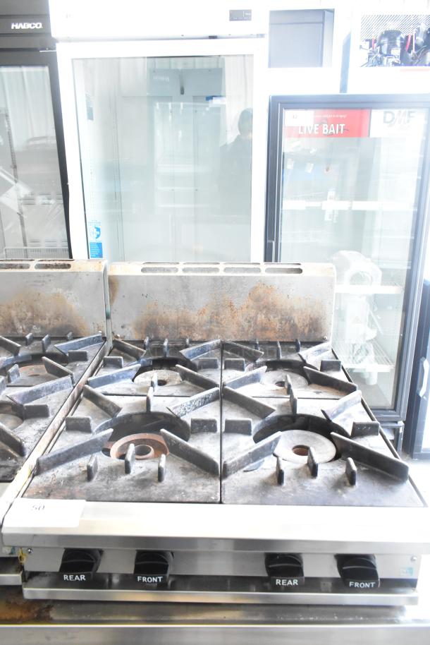 BT60-4N Commercial 4 Burner Gas Range, slightly worn grates, stainless steel body. Control knobs labeled for rear/front burners.