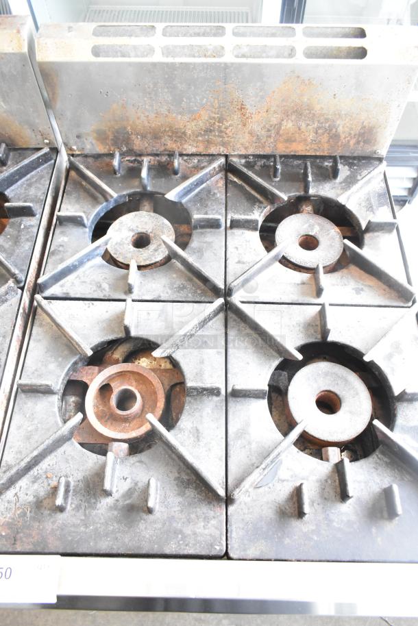 BT60-4N Commercial Gas Range, 4-burner, used, visible wear and rust, robust metal construction. Ideal for high-capacity cooking.