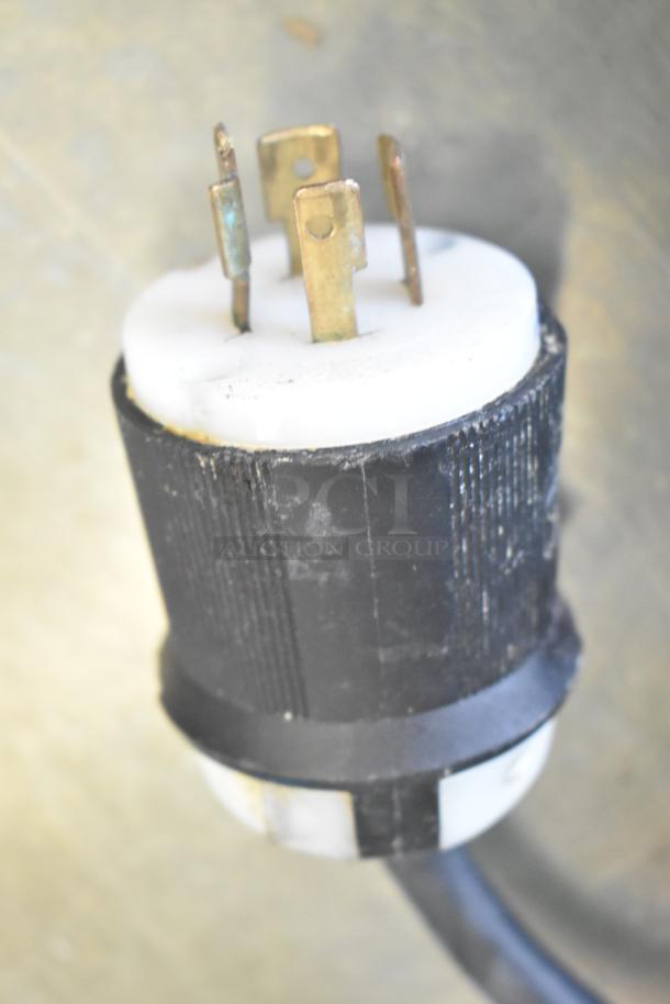 Close-up image of a black and white plug with brass prongs for the 2020 CookTek MSP7000-200 induction range.