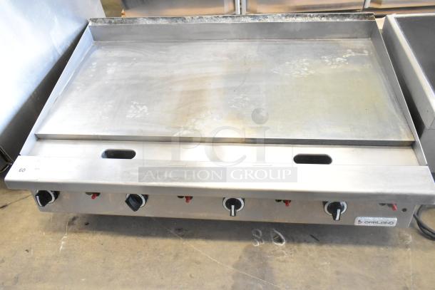 Garland commercial countertop flat top griddle, stainless steel, four control knobs, used condition, Garland brand label visible.