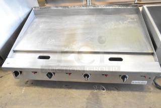 Garland commercial countertop flat top griddle, stainless steel, four control knobs, used condition, Garland brand label visible.
