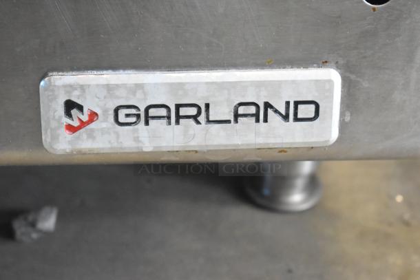 Garland Commercial Countertop Flat Top Griddle with visible brand label, stainless steel, used condition, sturdy foot support.