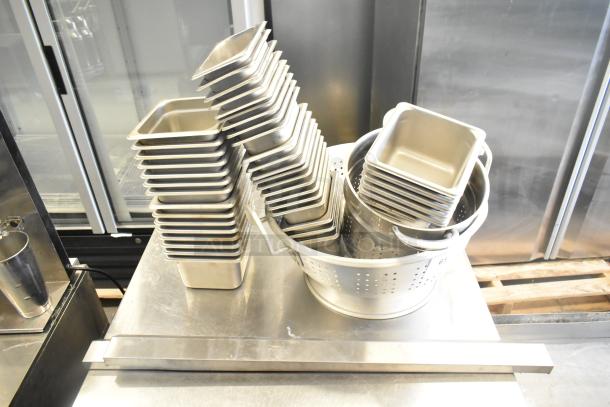 47 stainless steel drop-in bins and colanders, stacked. Includes various sizes, with visible perforations for drainage.