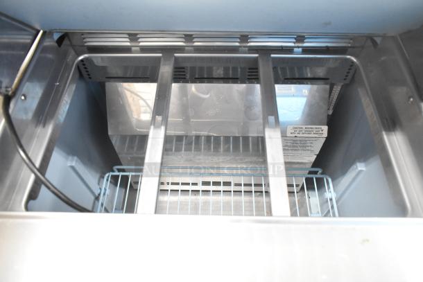 Delfield 4427N-6-DHL-BR2 prep table interior, shows open storage, cooling vents, and caution label. Good condition.